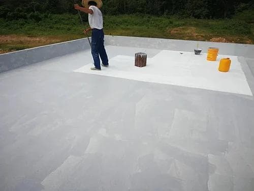 Worker rolling white waterproofing membrane onto a flat roof