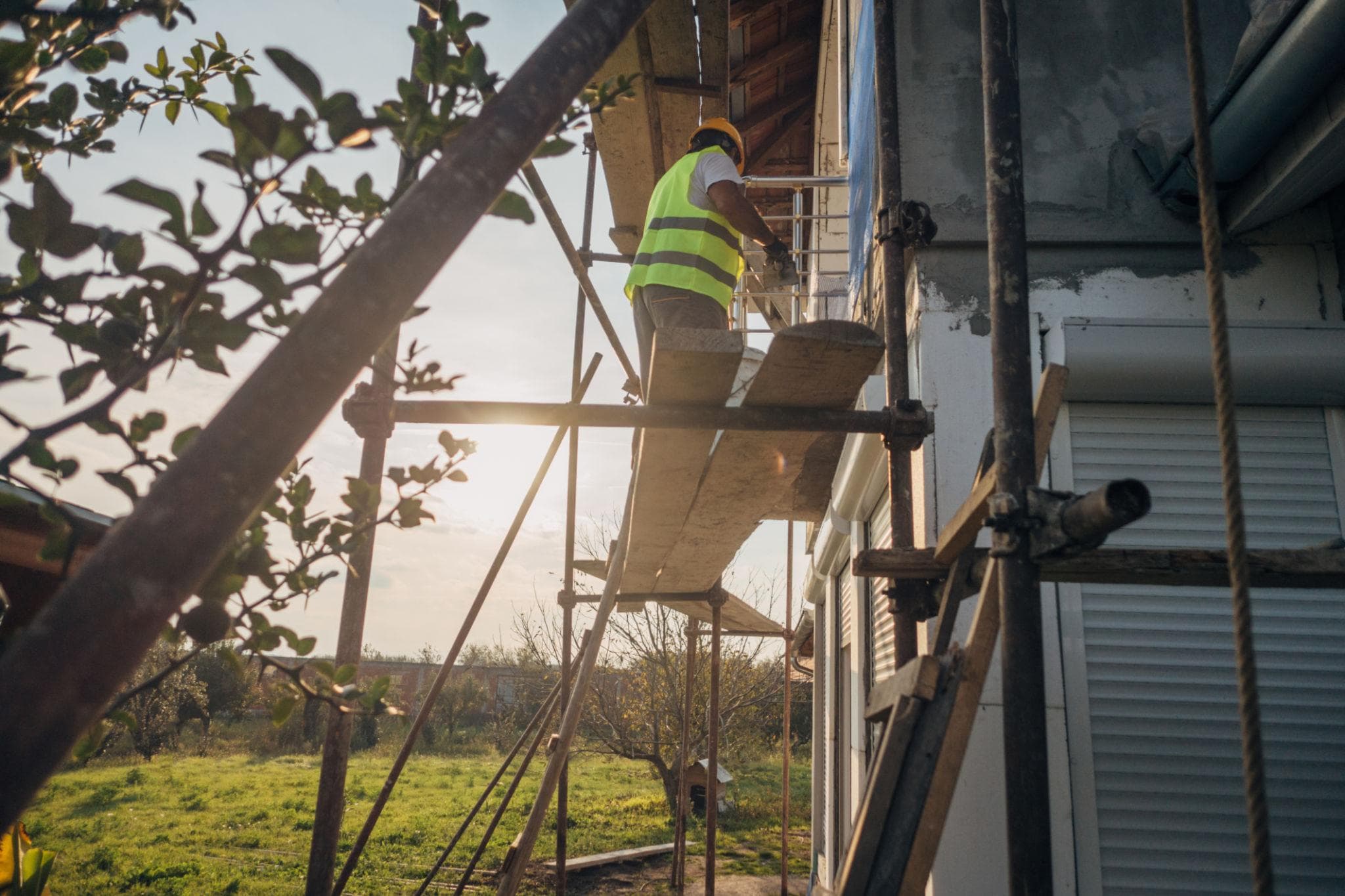 Worker applying exterior wall finish from scaffolding